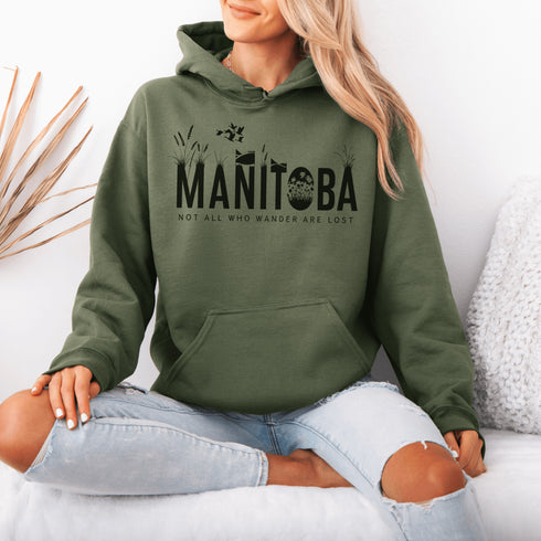 Featuring a serene prairie landscape, the design captures the essence of the heartland with wildflowers and prairie grasses growing out of the letters Manitoba.